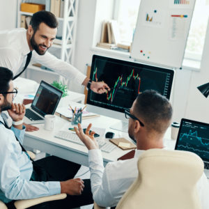 Stock market. Group of young modern men in formalwear analyzing stock market data while working in the office